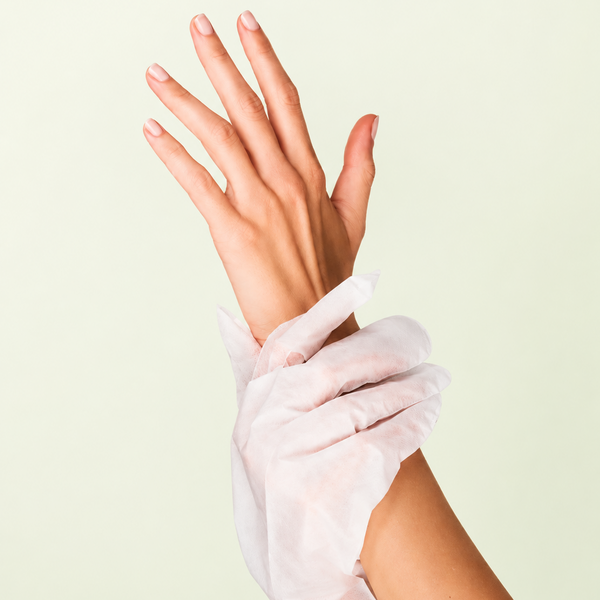 Woman wearing Rivahna Spa Gloves during a moisturizing hand treatment, featuring removable fingertips for manicure services and nail care.